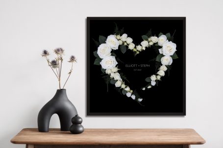 Personalised floral heart artwork on black with white roses and asparagus ferns, styled with modern decor.