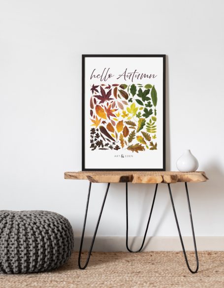 Hello Autumn artwork featuring colourful autumn leaves in shades of red, yellow, green, and brown, displayed in black frame on wooden table